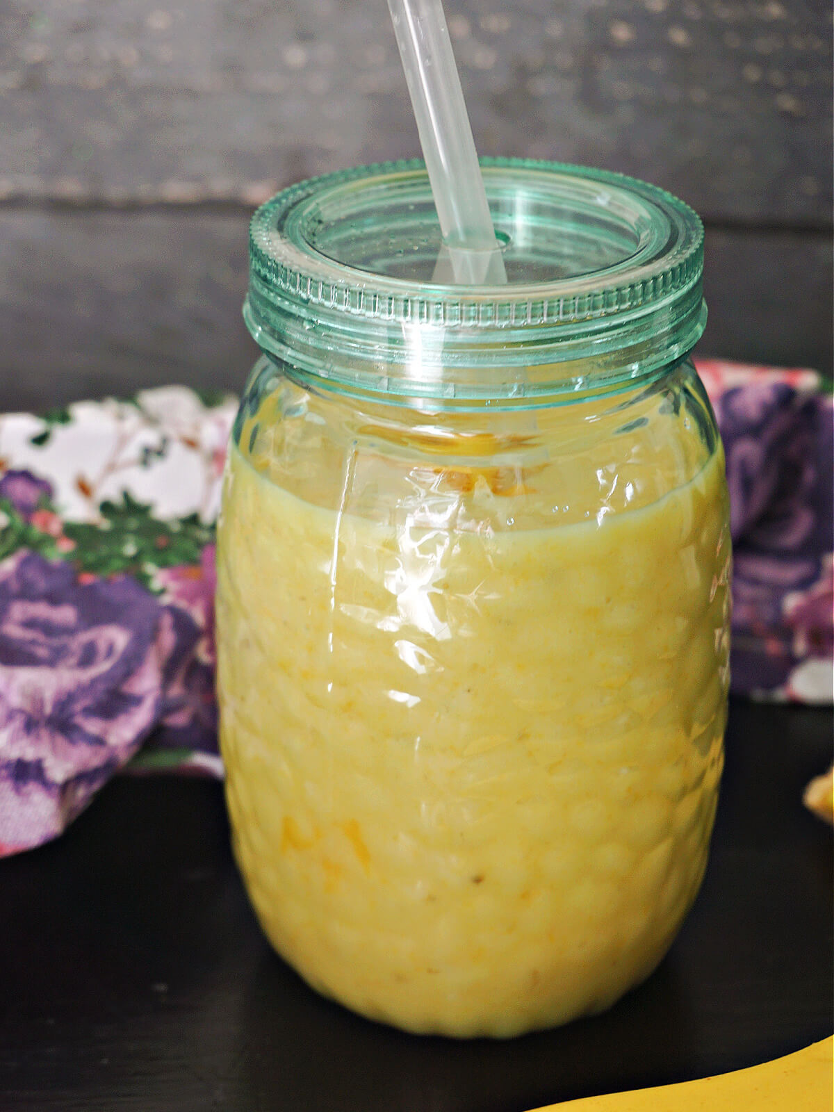 A glass with mango and banana smoothie.
