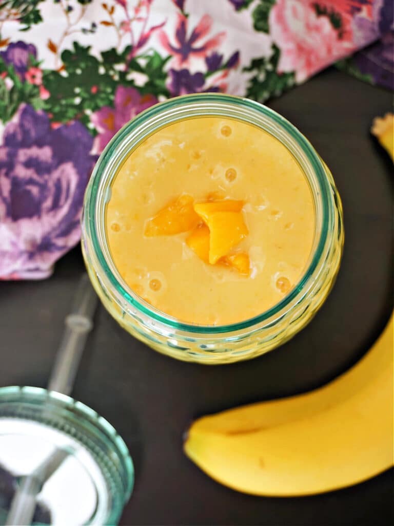 Overhead shoot of a glass with mango and banana smoothie