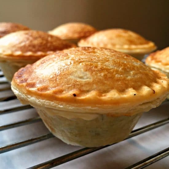 A close shot of a mini mushroom pie on an oven rack with other pies in the background