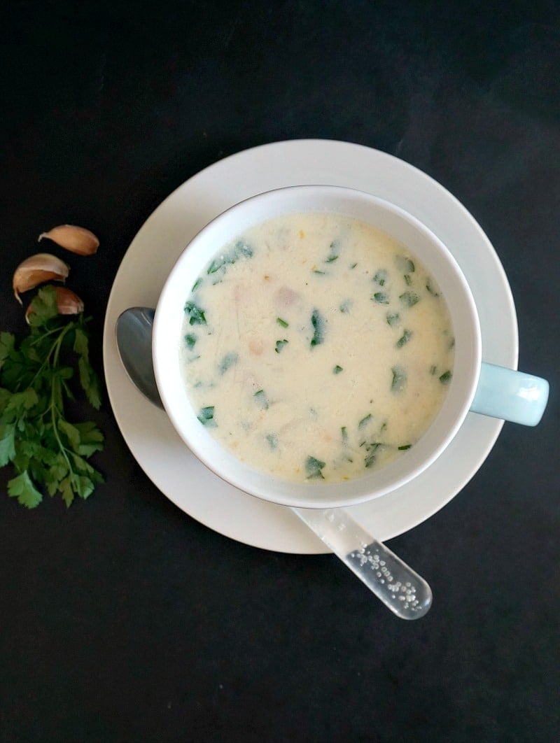 Overhead shoot of a white bowl of chicken soup with garlic and sour cream
