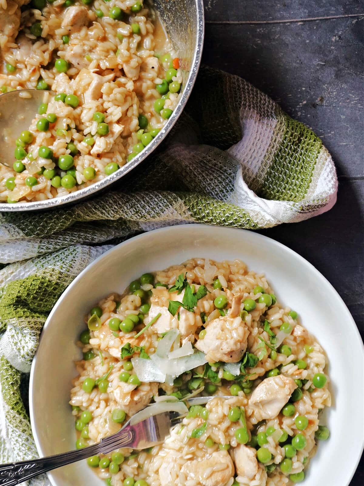 Overhead shoot of a white bowl of risotto with a pan of more risotto at the top.