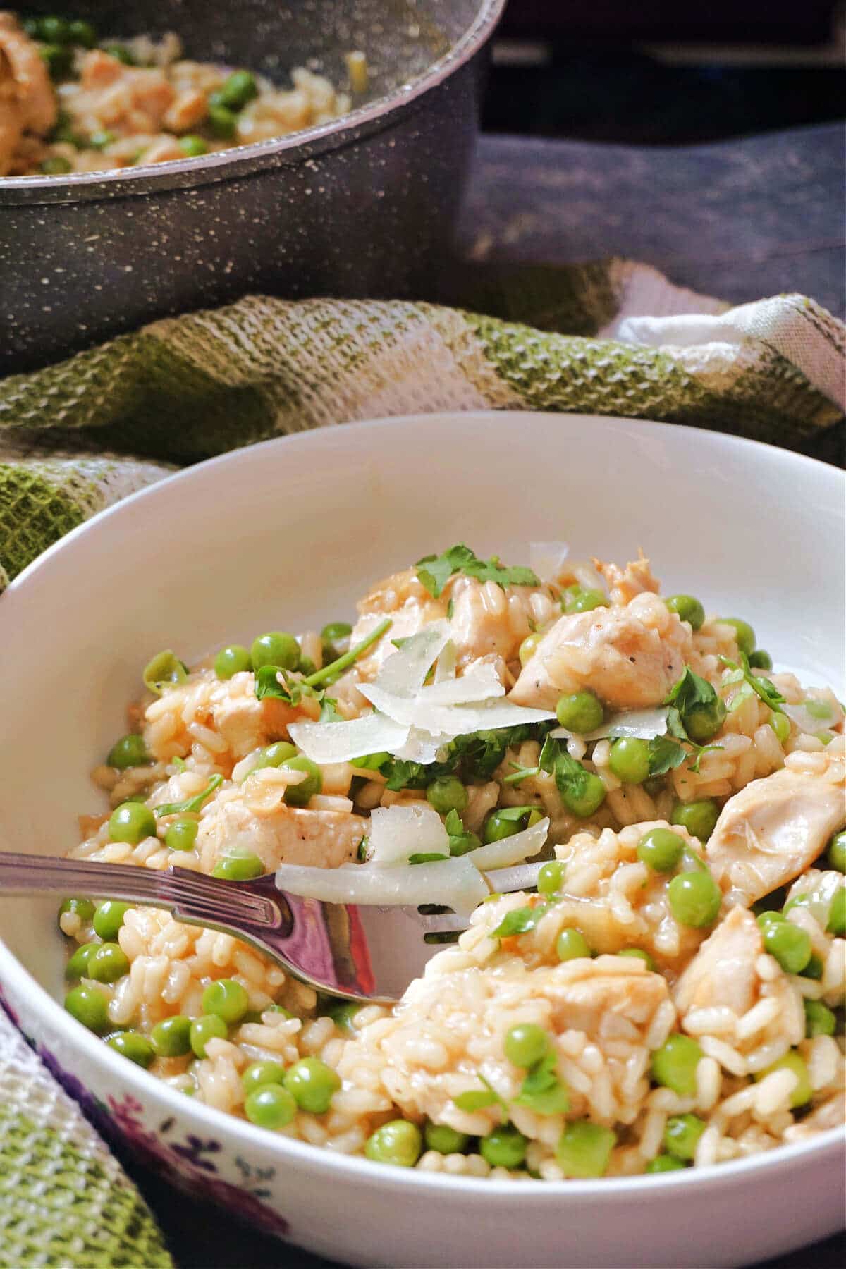 A white bowl with chicken and pea risotto.