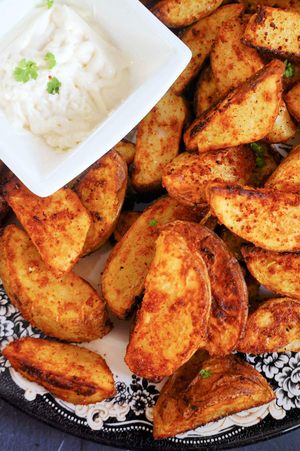 Close-up shoot of potato wedges next to a small white bowl of mayo