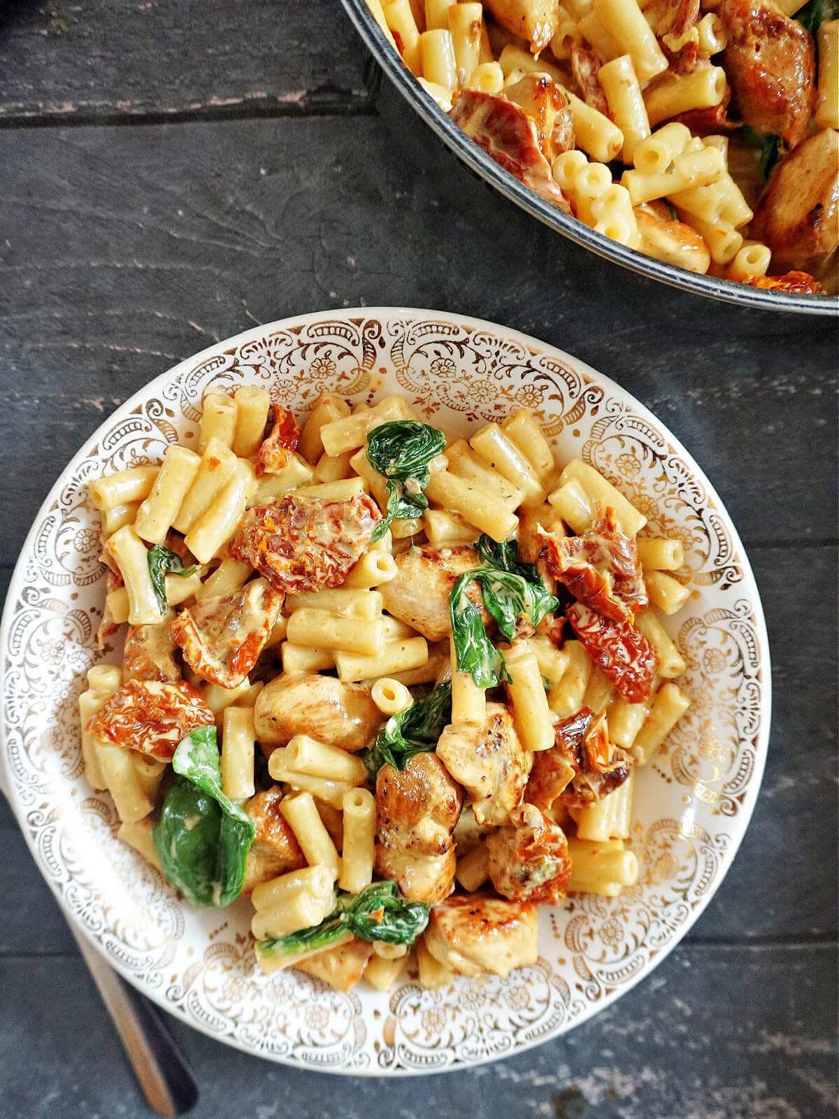 Overhead shot of a plate with pasta with sun-dried tomatoes and spinach.