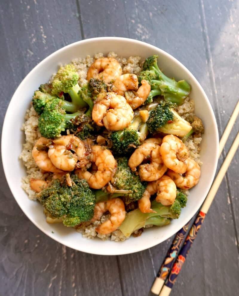 Overehead shoot of a white bowl with shrimp and broccoli and chopsticks on the side.