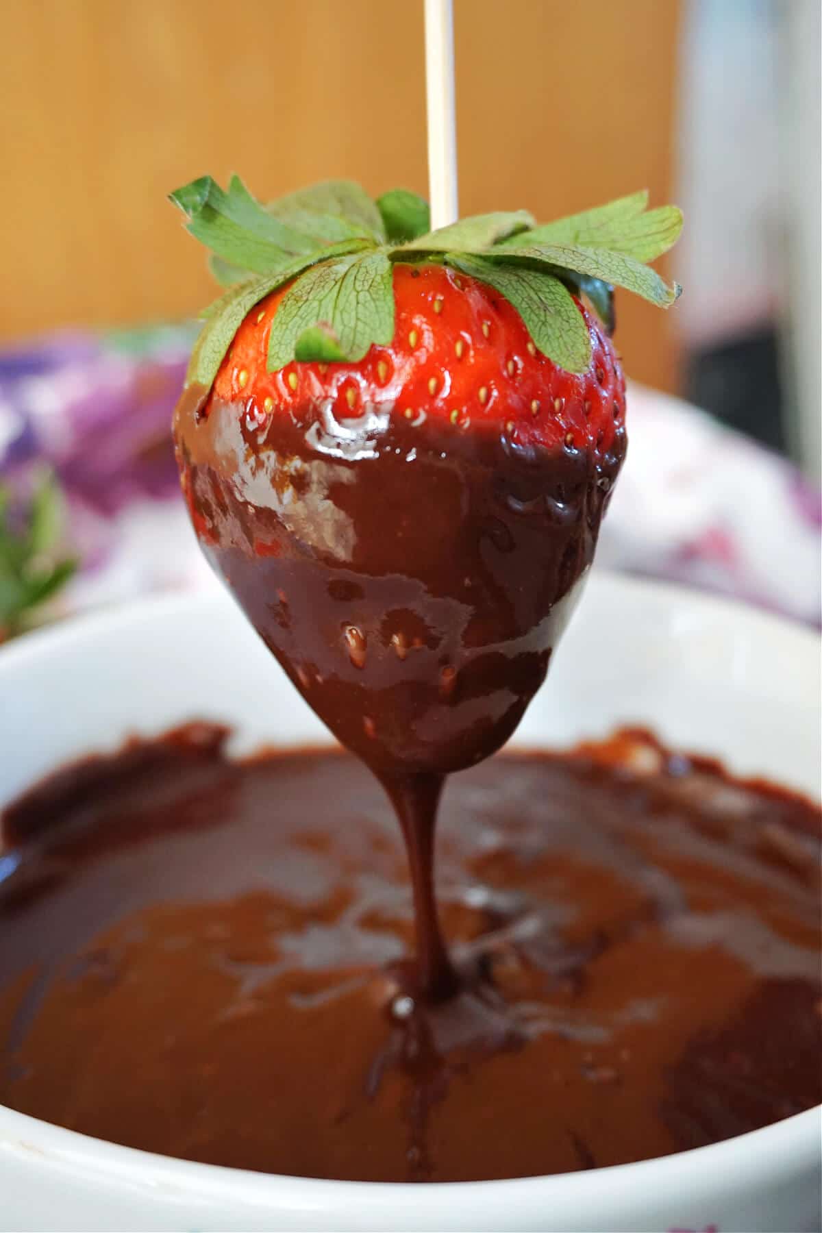 A strawberry being dipped in chocolate sauce.