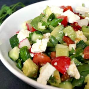 A white bowl with feta and veggie salad