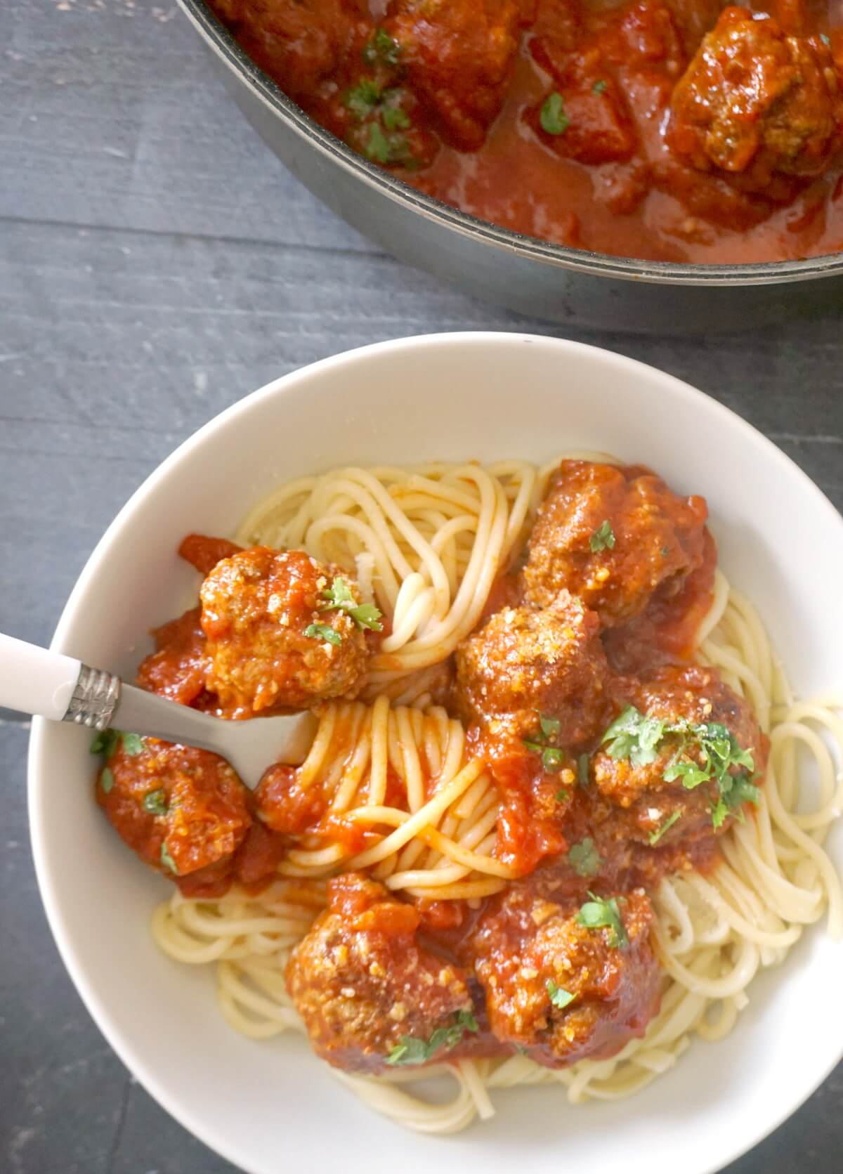 Overhead shoot of a white bowl of spaghetti and meatballs.