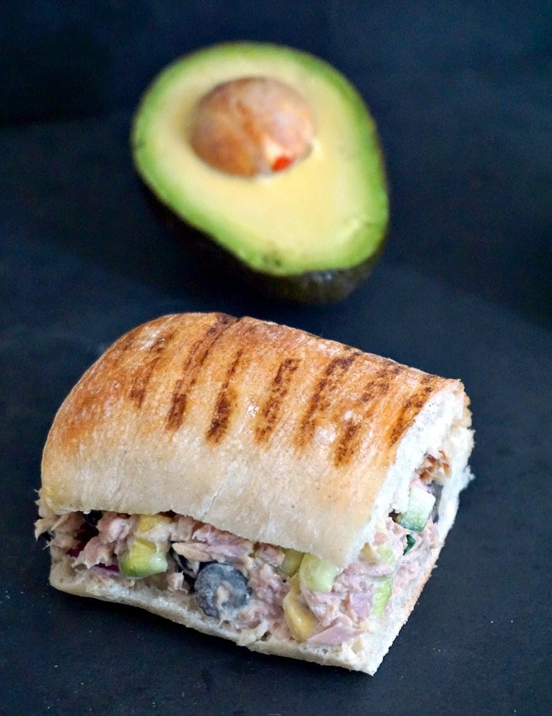 A tuna salad sandwich and half an avocado