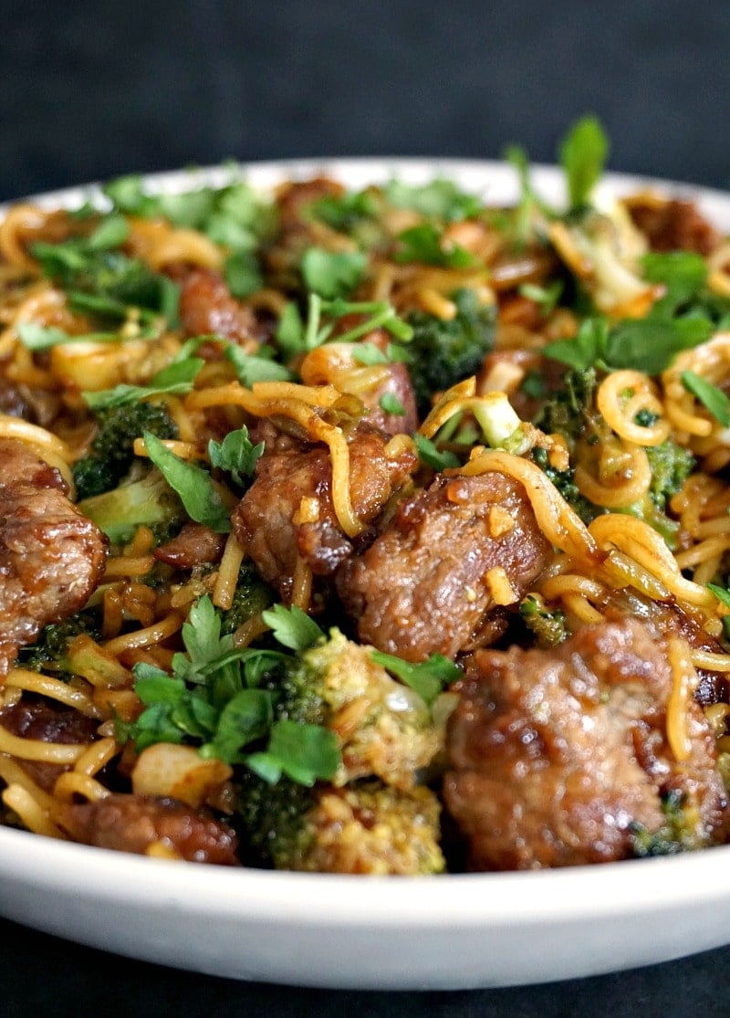 Close-up shoot of a white plate with broccoli and beef noodles.