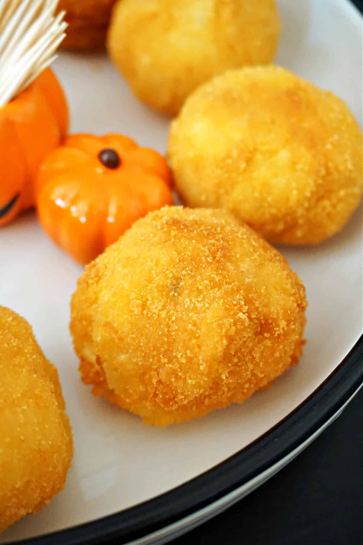 Close-up shoot of arancini balls on a white plate.