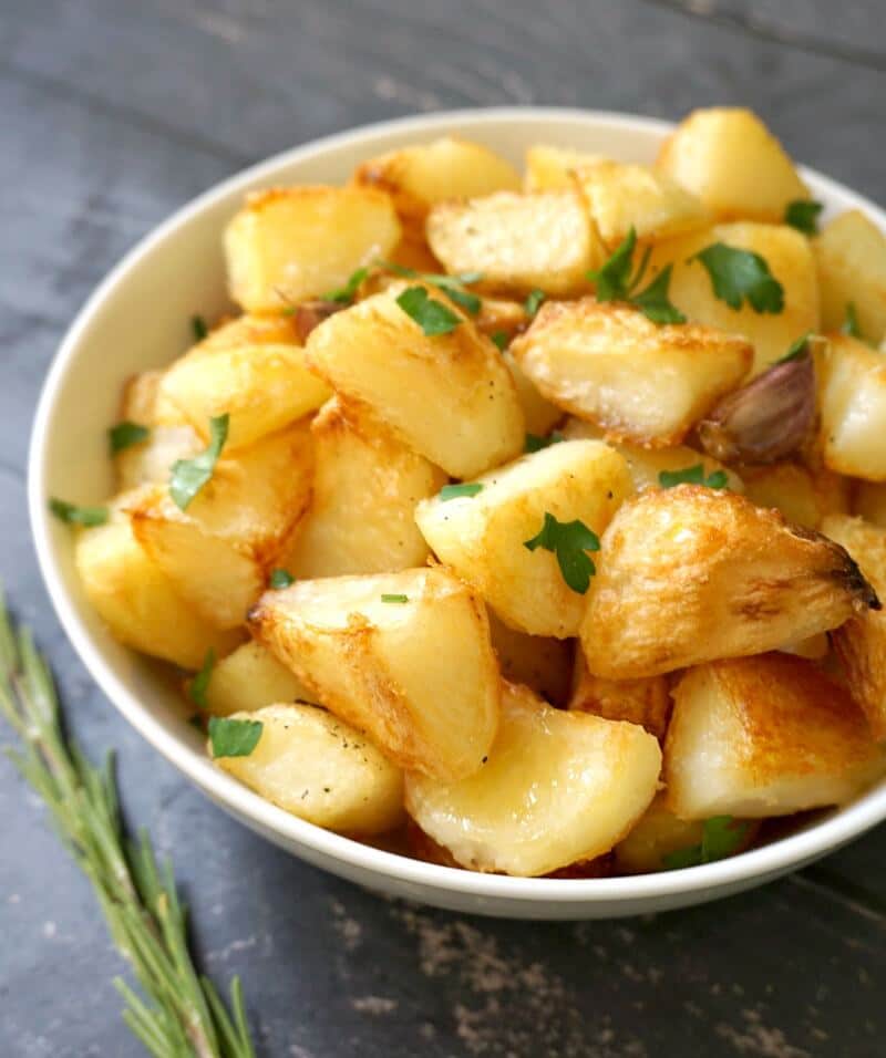 A white bowl with roasted potatoes
