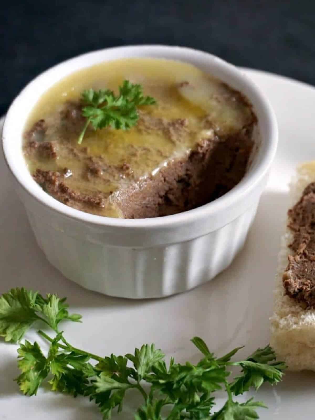 A white ramekin with chicken liver pate.