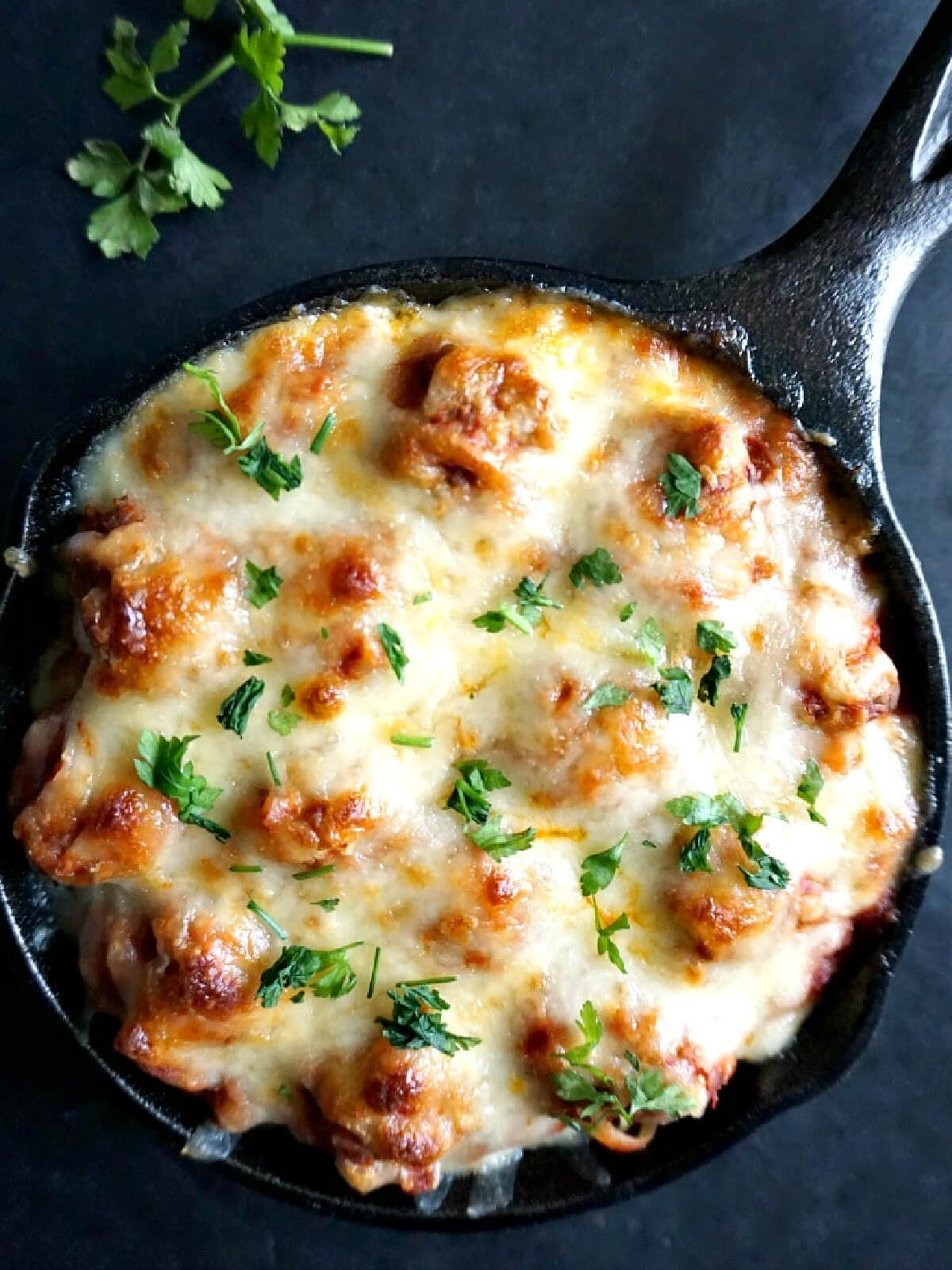 A skillet with baked meatballs and spaghetti.