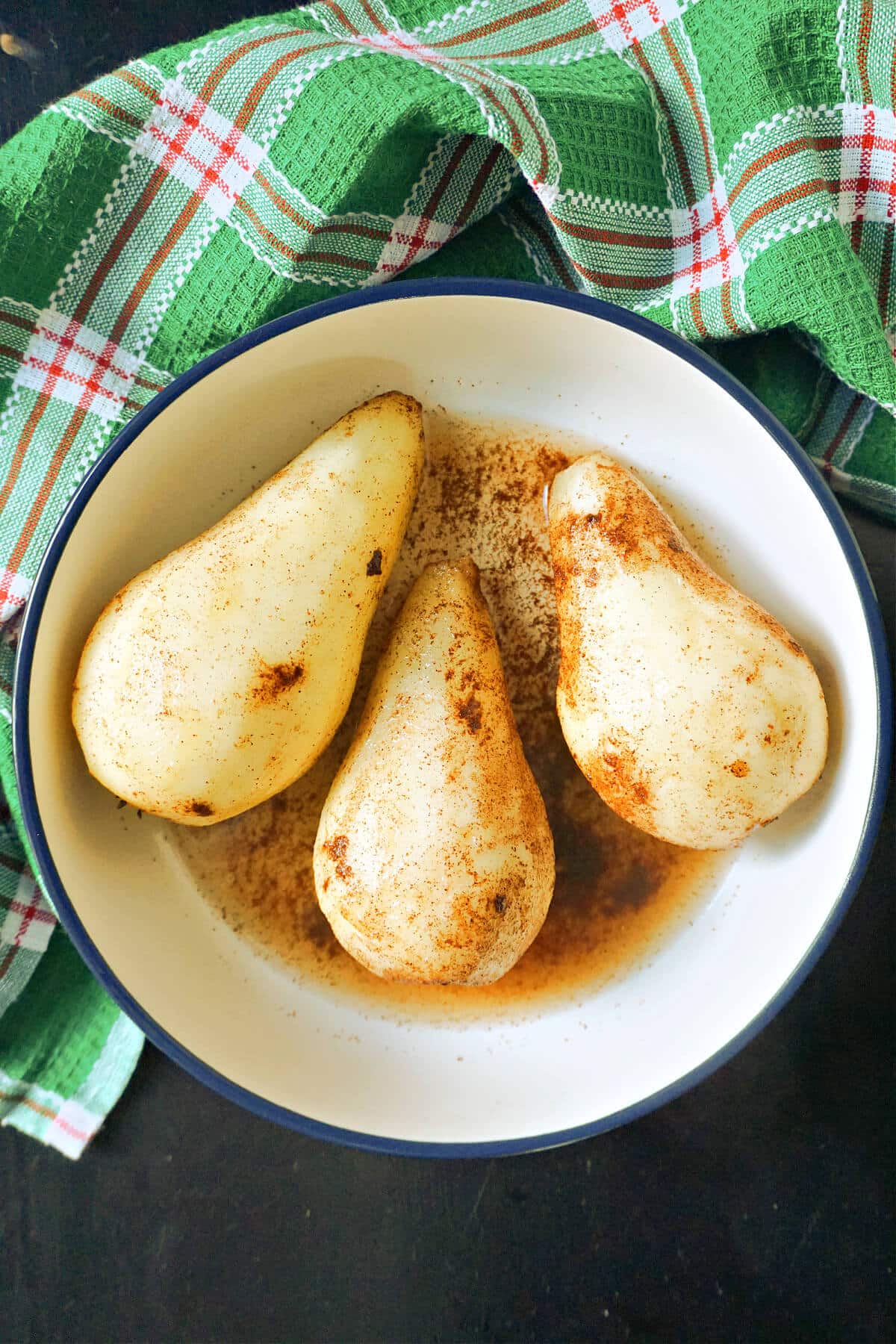 A bowl with 3 skinless pears with cinnamon on them.