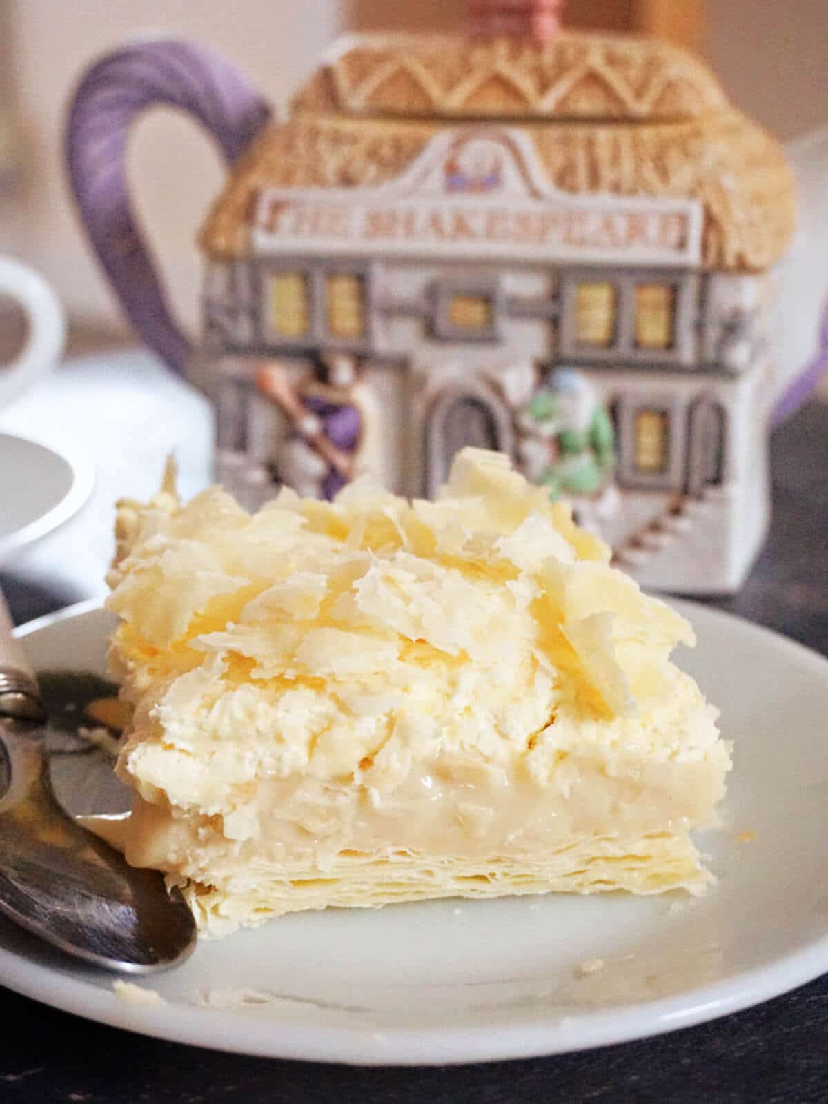 A white dessert plate with a slice of cremeschnitte on it.