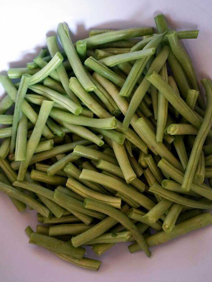 Trimmed green beans in a white bowl.