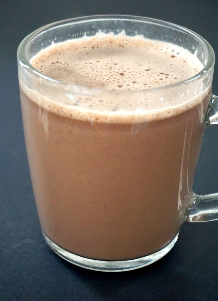 A glass of homemade hot chocolate on a black background.