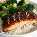Baked teriyai salmon with sesame seeds and broccoli on a bed of rice.