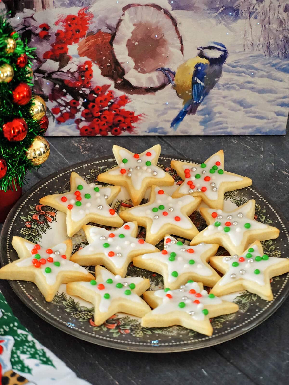 A plate with star cookies with festive decorations around.