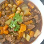 A white bowl with beef and sweet potato stew