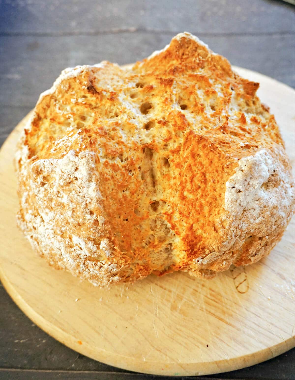 A soda bread on a round wooden board.