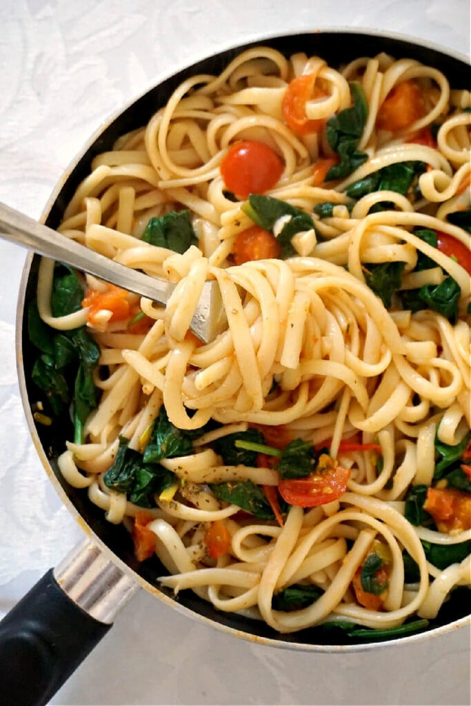 Overhead shoot of a pan with spaghetti with spinach and tomatoes