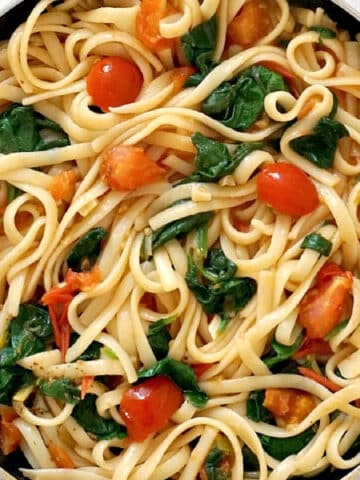 Overhead shoot of a pan with linguini, tomatoes and spinach