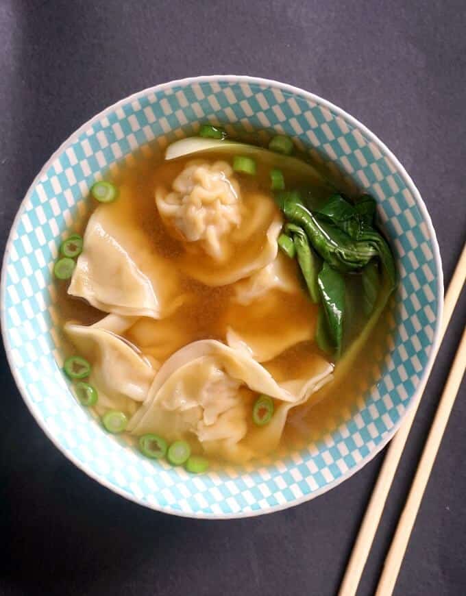 Overhead shot of a bowl of wonton soup with chopsticks on the side