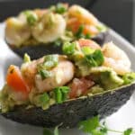 2 avocado skins filled with salad on a white plate
