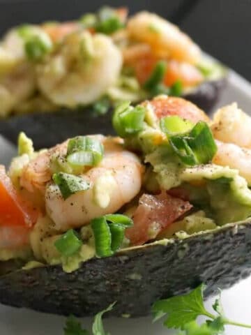 2 avocado skins filled with salad on a white plate