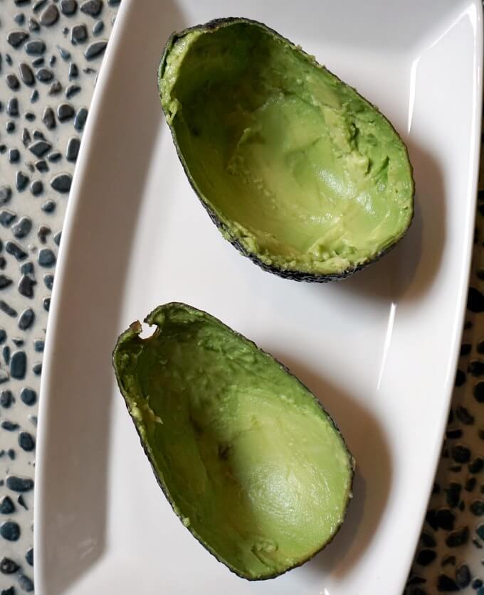 2 avocado skins on a white plate.