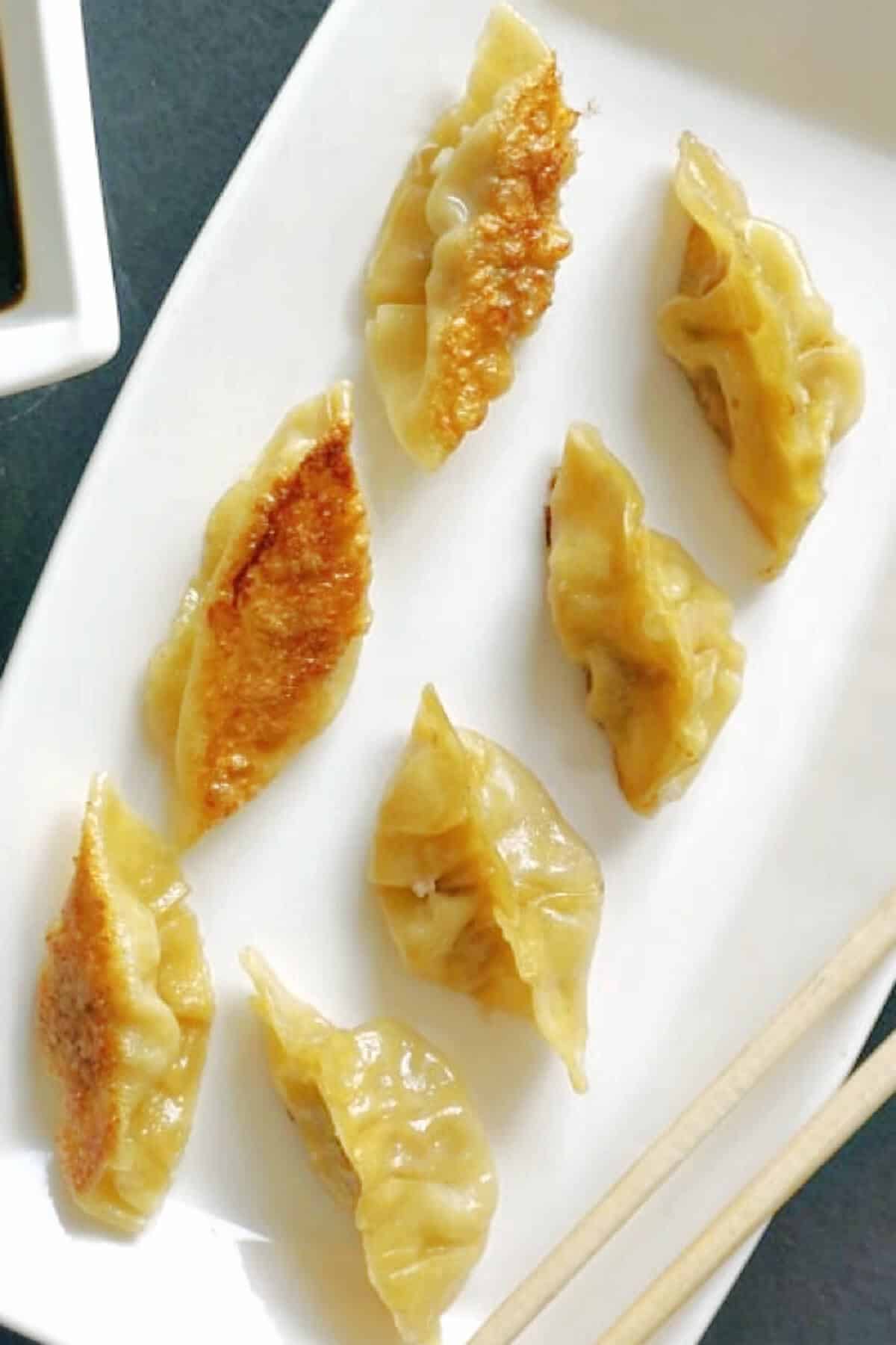 A white plate with 7 Chinese dumplings.
