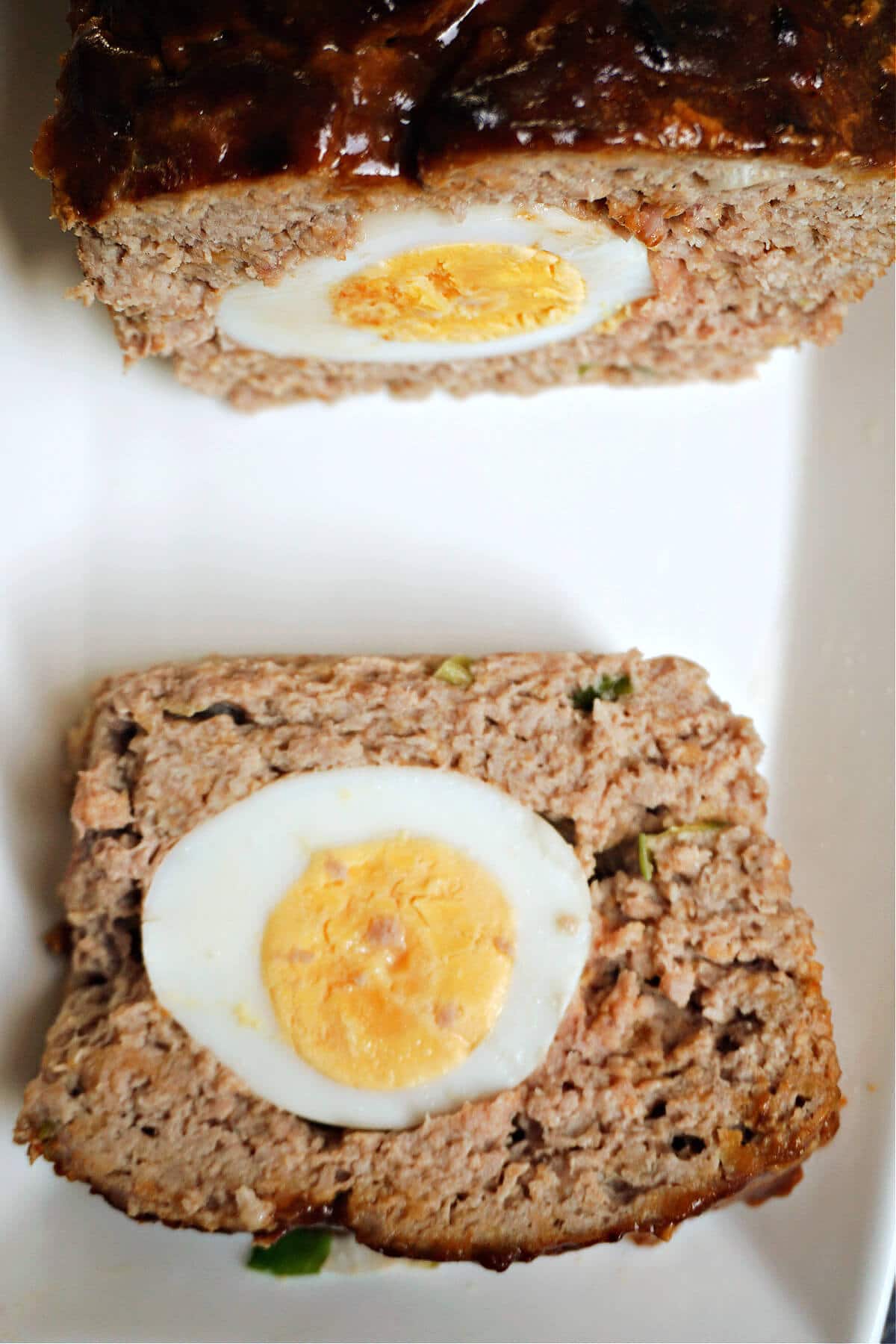 A slice of meatloaf with a slice of boiled egg in the middle.