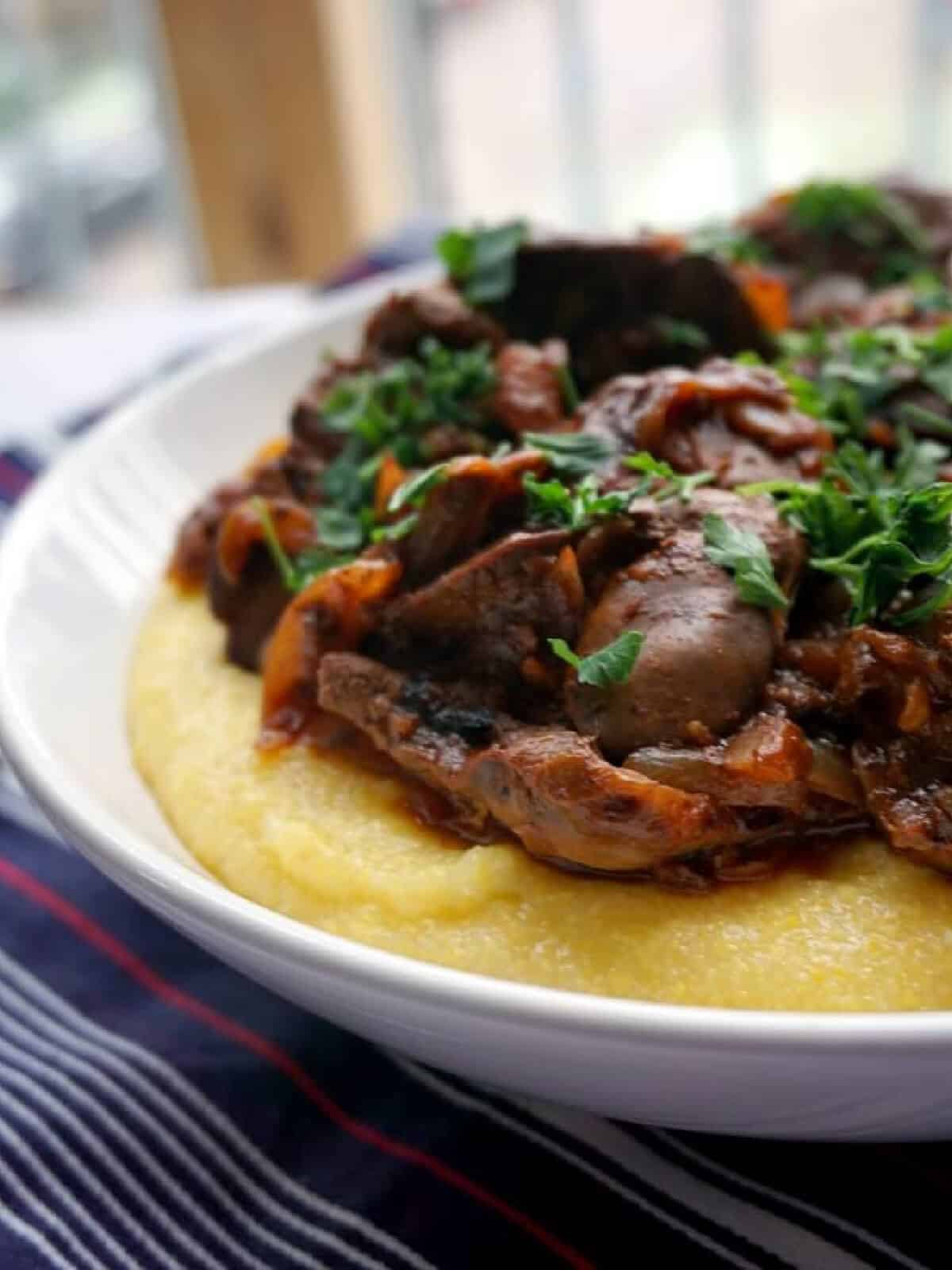 A white bowl with polenta and chicken livers.