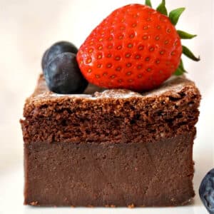A slice of chocolate magic cake topped with a strawberry and 2 berries