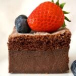Close-up shot of a slice of chocolate magic cake tiopped with berries