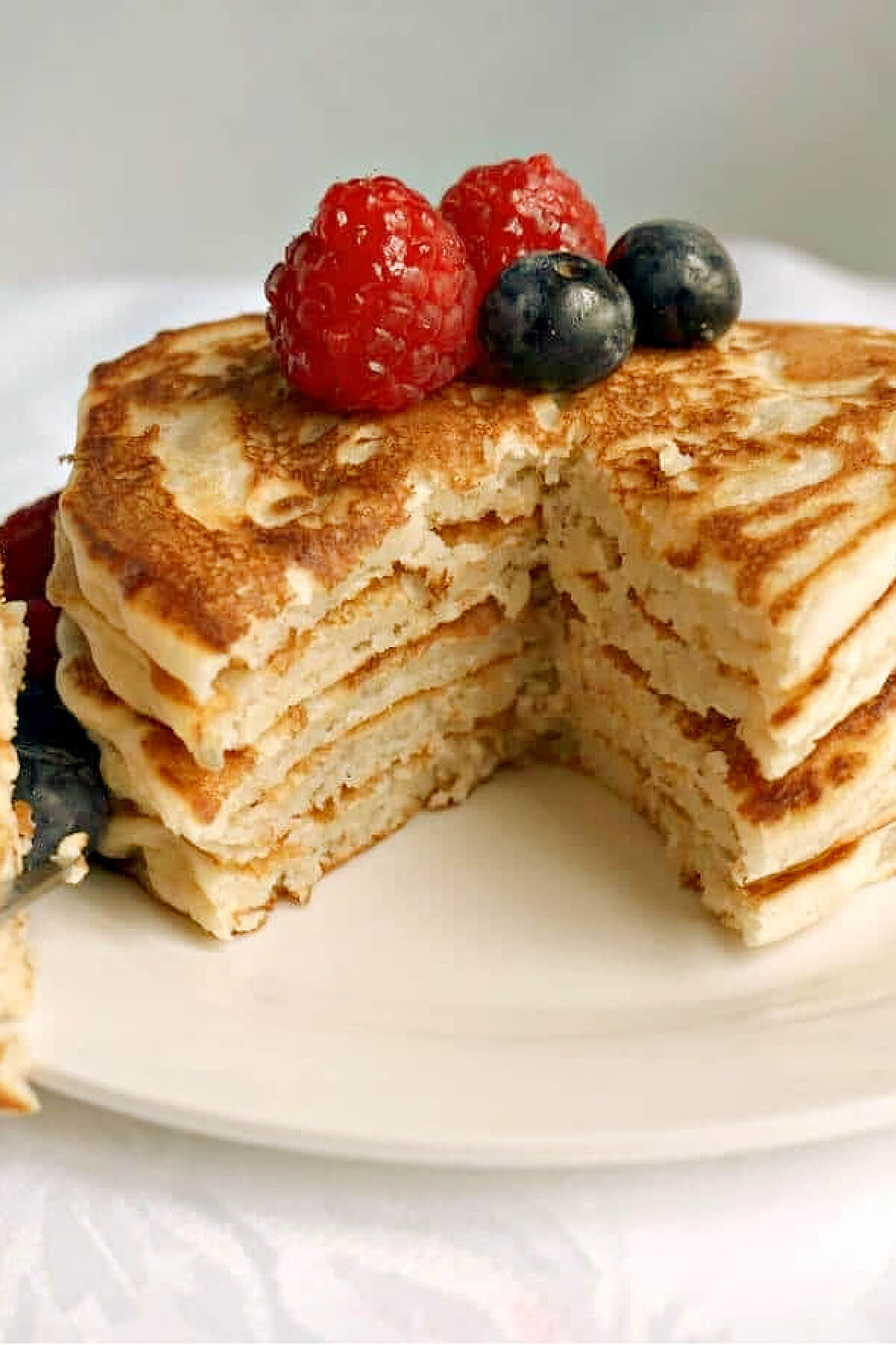 A pile of pancakes cut into, and topped with berries.
