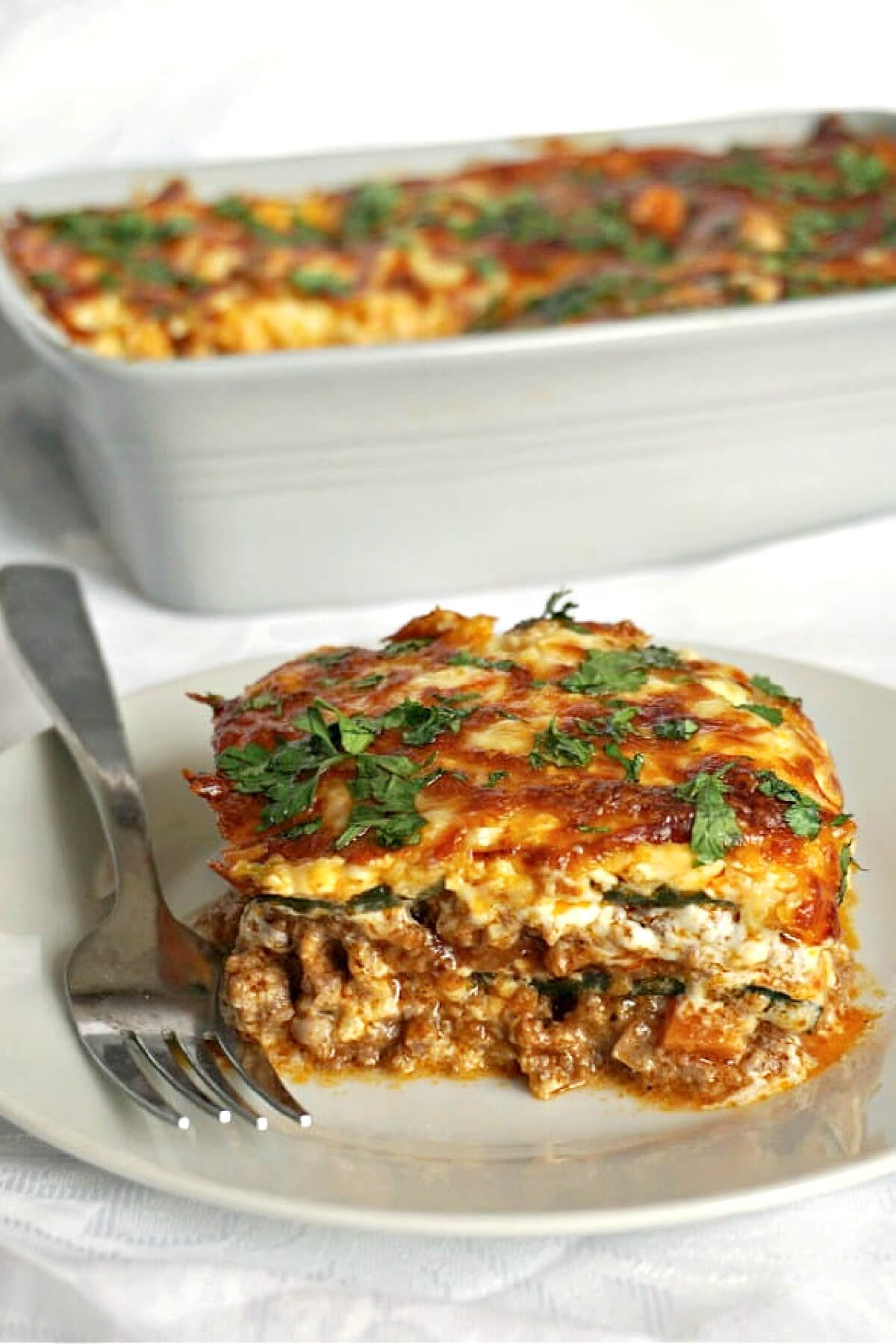 A slice of lasagna on a white plate.