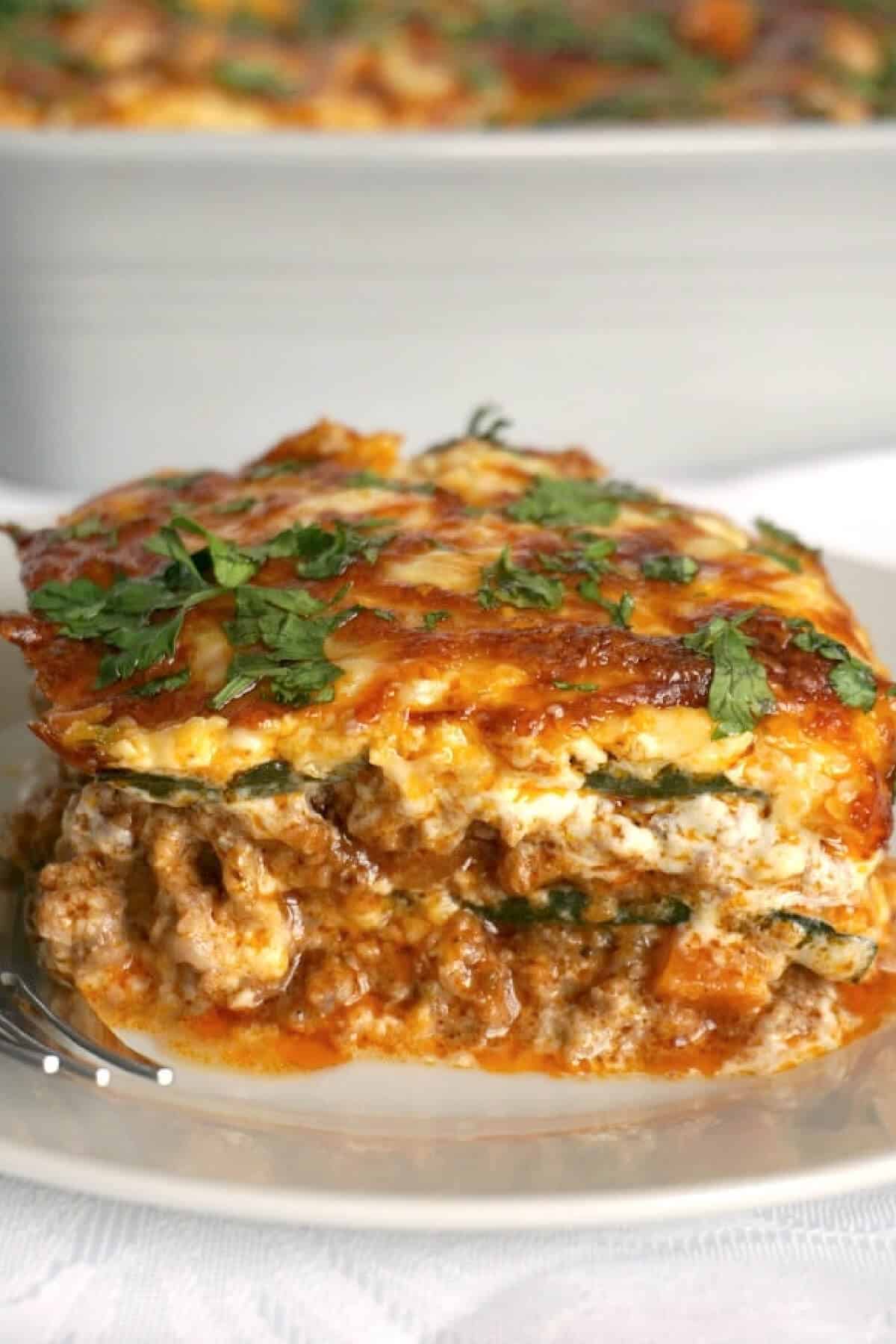 A slice of lasagna on a white plate.
