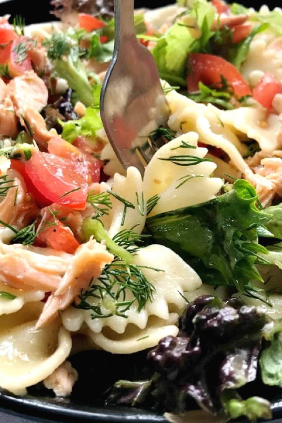 Close-up shoot of a pasta salad with salmon and veggies.