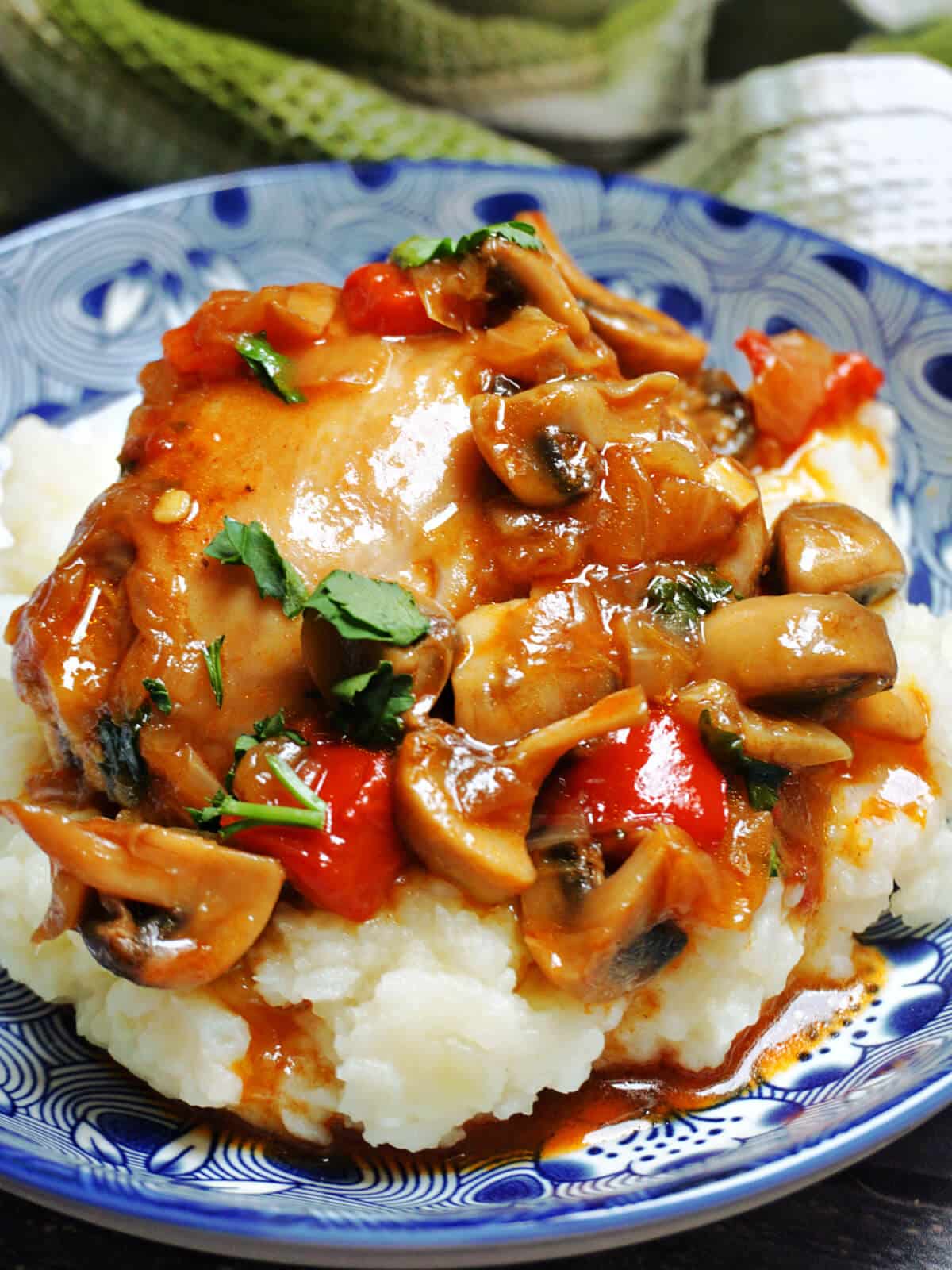 Close-up shoot of a blue plate with chicken and mushroom stew on a bed of mash.