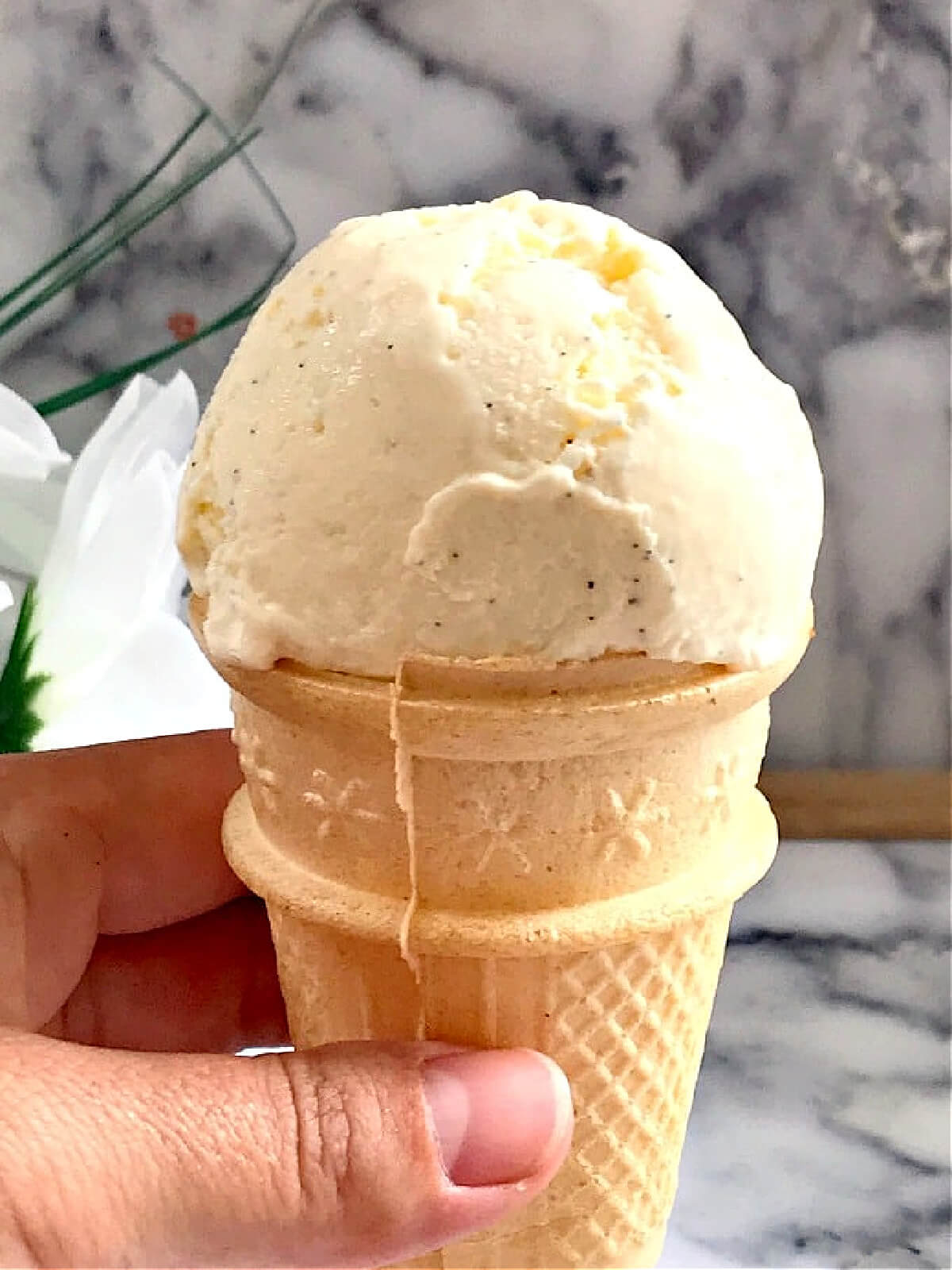 A cone of ice cream held by hand.