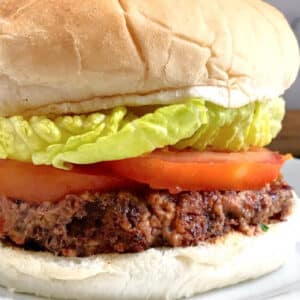 A bean burger in a bun with tomatoes and green salad