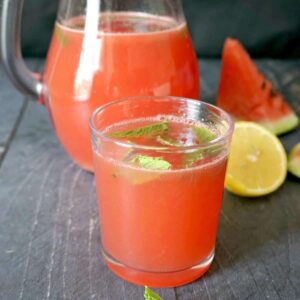 A glass of watermelon mint lemonade with a glass of lemonade in the background