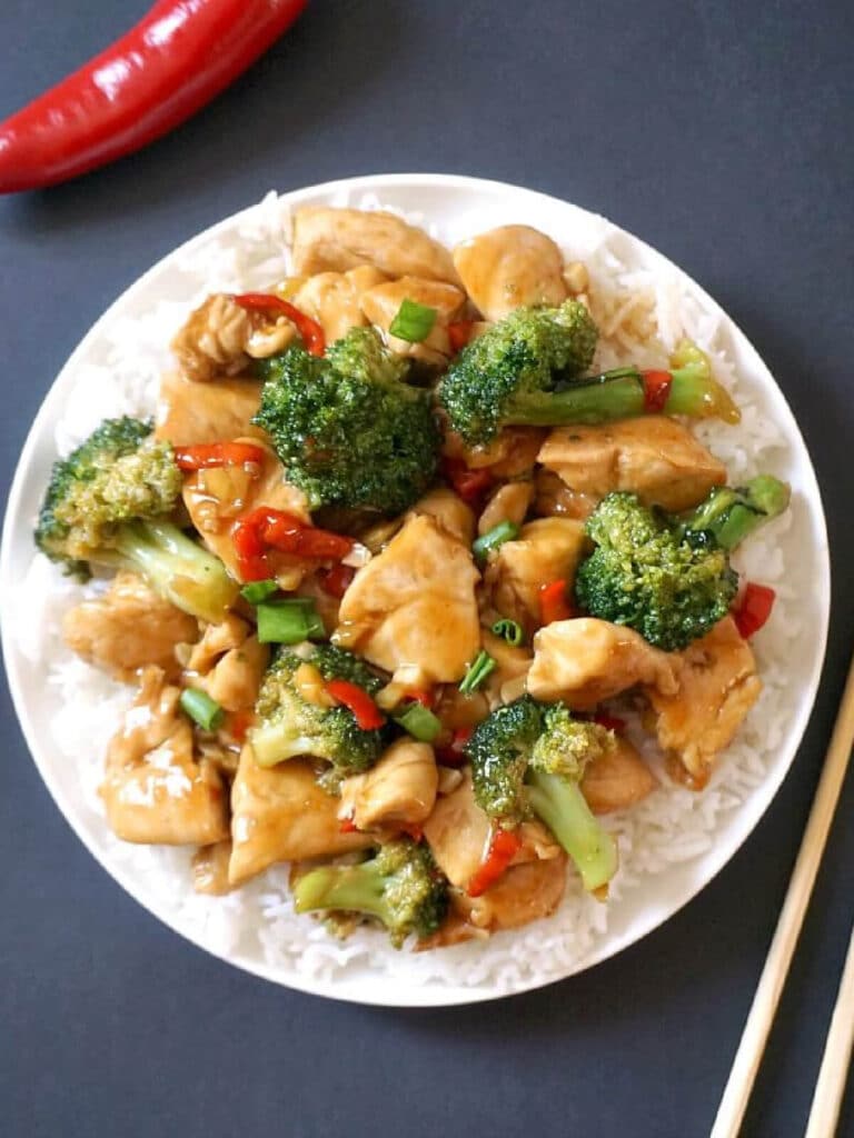 Overhead shoot of a white plate with chicken and broccoli stir fry over a bed of rice