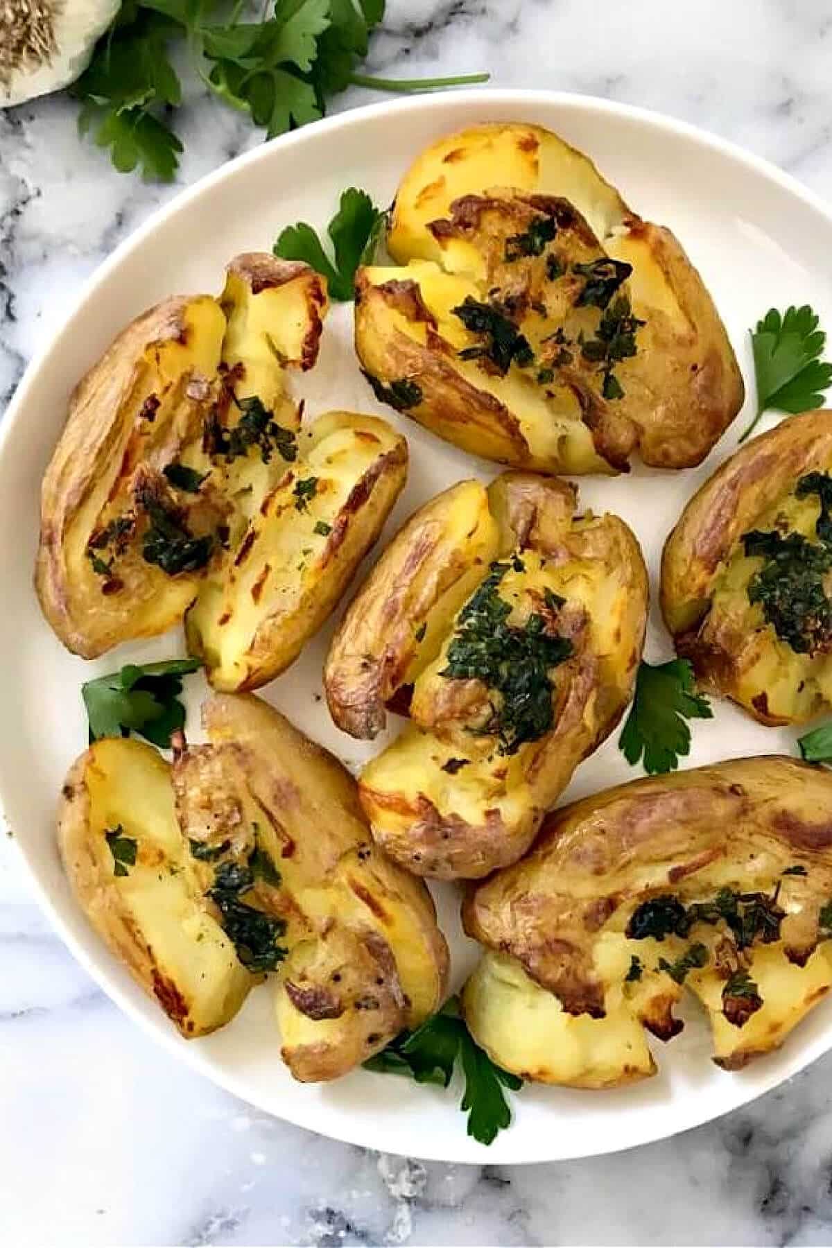 A white plate with crushed baby potatoes.