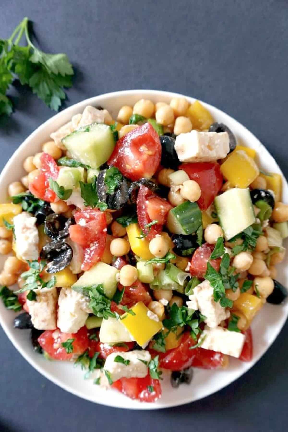 A white bowl with chickpea and veggie salad.