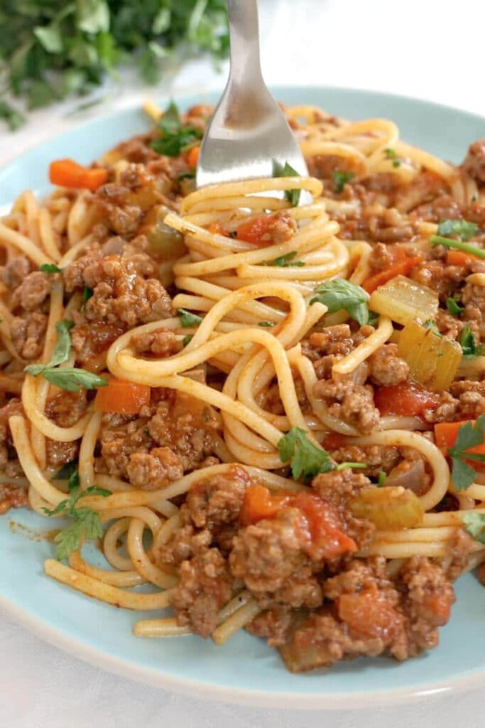 A light blue plate with spaghetti bolognese