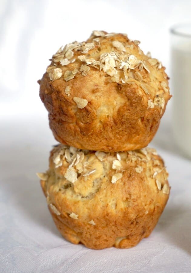 A stack of 2 banana muffins with a glass of milk in the background
